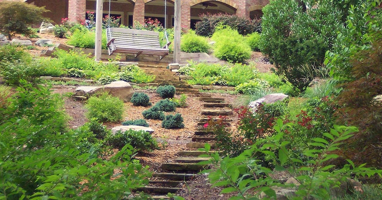 A Landscaped backyard with a stone path and many plants and bushes