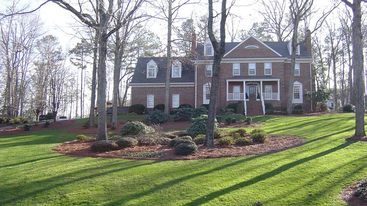 A red brick house on a hill with multiple landscaped areas